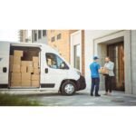 Delivery Man Gives Postal Package to a Business Customer, Who Signs Electronic Signature POD Device. In Stylish Modern Urban Office Area Courier Delivers Cardboard Box Parcel to a Man